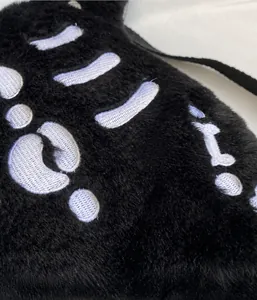 Détail macro du tissu peluche et de la broderie d'os sur le sac à dos tête de mort noir