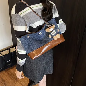 Contrast denim and brown leather tote bag with chain strap and teddy bear pendant