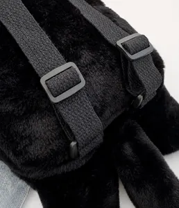 Détail de la boucle réglable en plastique et de la sangle noire du sac à dos en peluche