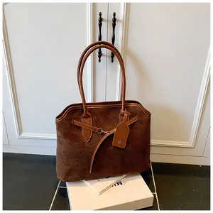 Detail van de koffiebruine suède tote bag met zilveren gespen en dubbele handvatten