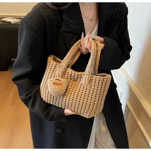 Détail du sac cabas beige tricoté à la main avec breloque cœur et étiquette en cuir