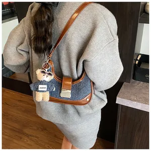 Detail of denim and brown leather crescent bag with cute teddy bear charm pendant