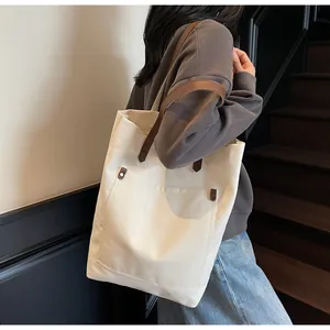 Detailed shot of canvas tote bag featuring brown leather handles and vintage metal rivets