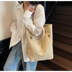 Detailed macro view of beige canvas tote bag with brown leather straps and front pocket