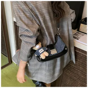 Detail of tweed crescent shoulder bag with metallic buckle and cute bear charm pendant