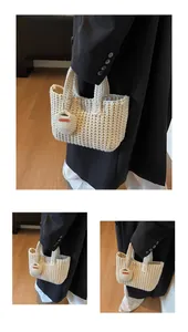Détail d'un sac cabas crème tissé main avec textures verticales et breloque artisanale