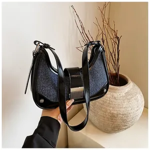 Close-up of denim and patent leather patchwork on a stylish crescent shoulder bag