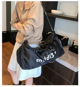 Detail of black Oxford travel bag with sturdy handles and white letter print for fitness