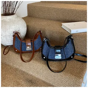 Detail of denim and leather crescent bags with silver metal buckles on a stone step