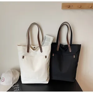Detail view of large canvas tote bags with leather handles and functional front pockets