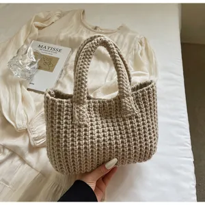 Gros plan du sac à main en maille épaisse beige montrant la texture de laine et les anses