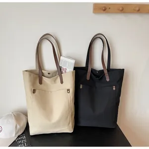Close-up of canvas tote bags with leather handles and rivet pocket for daily commute