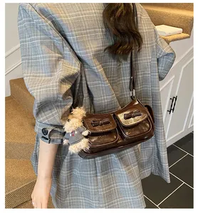 Detail of dark brown glossy crossbody bag with bow accents and a cute teddy bear charm