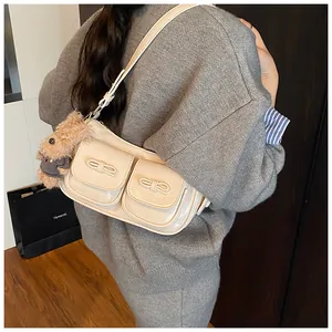 Detail of cream white shoulder bag with leather bows and brown plush teddy charm