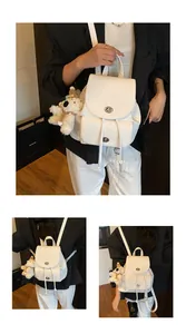 Detail eines weißen PU-Lederrucksacks mit Lychee-Struktur und Bären-Anhänger-Zubehör