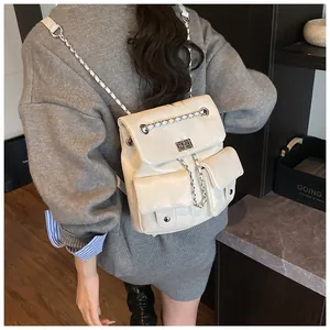 Close-up of white faux leather backpack featuring silver chain straps and metal twist lock