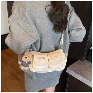 Cream shoulder bag with two bow pockets and a cute plush bear charm in detailed view