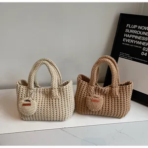 Détail de sacs à main en tricot faits main en beige et marron avec pendentifs cœur
