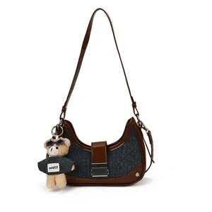 Denim crescent shoulder bag with brown leather trim and cute plush bear charm decoration