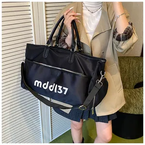 Close-up of black Oxford cloth travel bag with white logo carried by a model