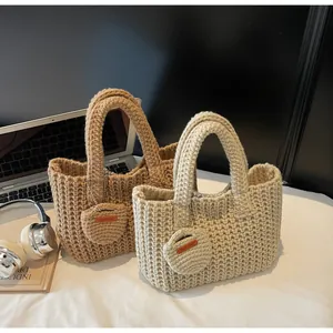 Détail de sacs fourre-tout en tricot faits main en beige et marron avec pendentifs