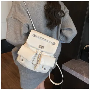 Detail of cream leather backpack featuring dual pockets, silver twist locks and chain straps