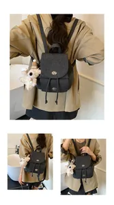 Detail eines grauen Canvas-Rucksacks mit Metalldrehverschluss und süßem Bärenanhänger