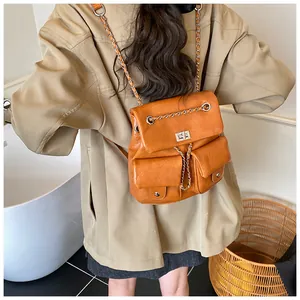 Detail of brown faux leather backpack with metal chain straps and front pockets