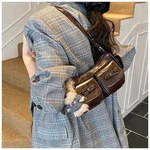 Detail of dark brown glossy shoulder bag with bow pockets and cute plush puppy pendant