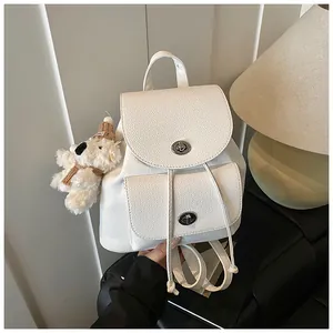 Dettaglio mini zaino bianco in pelle con chiusure in metallo argento e ciondolo a orsetto
