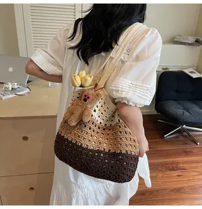 Detailed knit texture of a gradient crochet tote bag with a brown teddy bear charm