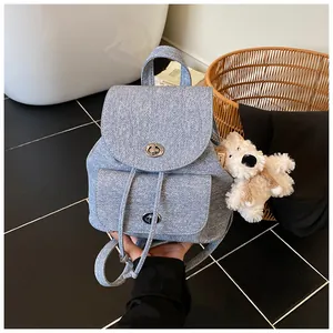 Dettaglio zaino azzurro trama denim con chiusure a scatto argentate e ciondolo a forma di cane