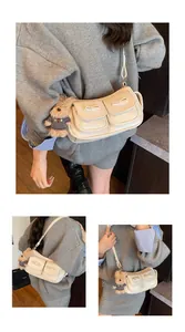 Detail of cream white leather underarm bag featuring decorative bows and cute bear pendant