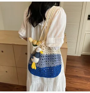 Close-up of tricolor crochet knit bag with seagull pendant and tulip flowers