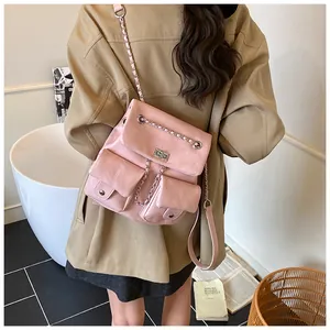Detail of pink faux leather backpack with chain accent and dual front flap pockets