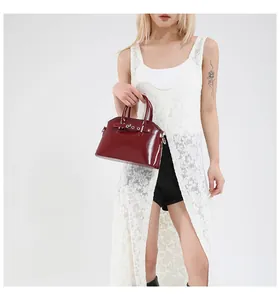 Detail view of burgundy shell bag with shiny leather texture and silver buckle accents