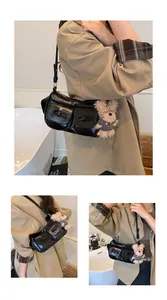 Detail of glossy black shoulder bag featuring dual front pockets and a cute plush bear charm
