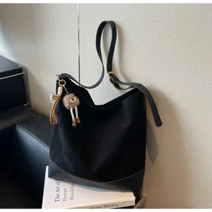 Detail of black suede hobo bag featuring leather patchwork and a cute bear charm