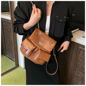 Detail of retro brown backpack featuring a metal twist lock and leather chain straps