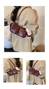Detail of burgundy leather shoulder bag with bow pockets and cute plush puppy charm