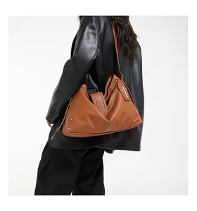 Bruine leren shopper met metalen klinknagels en kruishanger getoond door een model