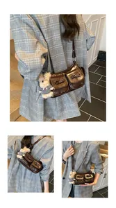 Detail view of a retro dark brown crossbody bag with bow accents and a plush bear charm