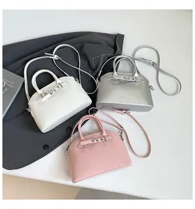 Detailed shot of white, silver, and pink shell-shaped crossbody bags on a grey suit jacket