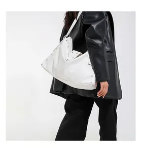 Detail van witte hobo-tas met lychee-structuur, metalen noppen en brede schouderriem