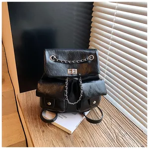 Detail of black textured PU leather backpack with silver chain decor and metal twist lock