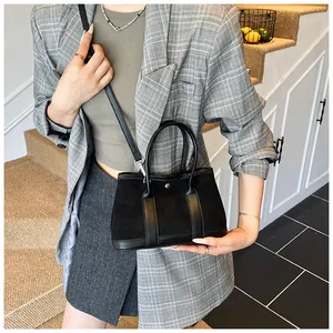 Detail of black suede and leather crossbody bag with metal ring buckle and strap