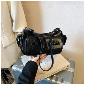 Detail of black patent leather shoulder bag with bow-knot pockets on a silver suitcase