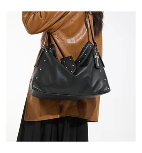 Detailopname van een zwarte leren hobo-tas met zilveren studs en een kruishanger