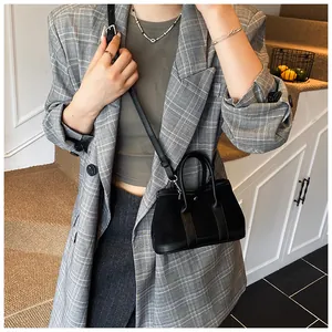 Detail of black faux suede tote bag with cylindrical handles and adjustable crossbody strap