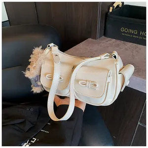 Macro view of beige leather shoulder bag showing bow pockets and plush bear charm